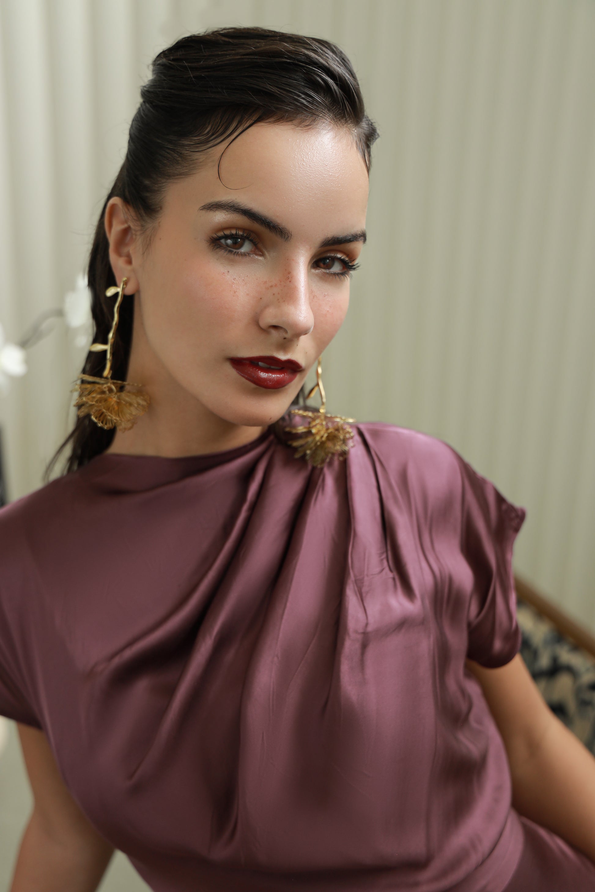 Woman wearing a mauve dress with a draped neckline.