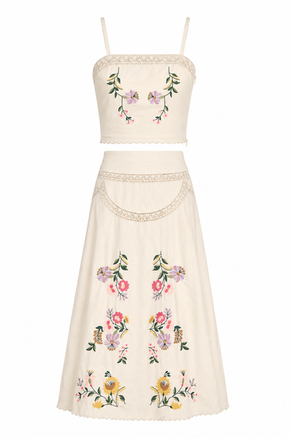 n off-white two-piece set consisting of a sleeveless crop top and a matching A-line skirt, both decorated with colorful floral embroidery and delicate lace trim.